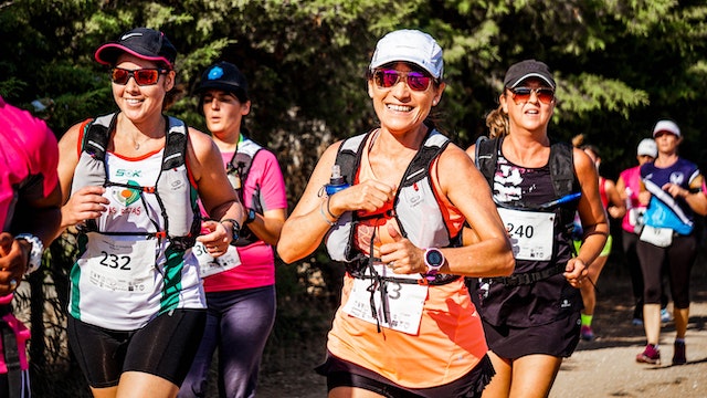 A group of women running a 5K race in bright sunshine