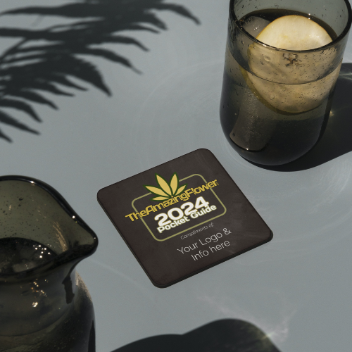 The 2024 TheAmazingFlower.com Cannabis & Hemp Co-branded Pocket Guide on a table with a glass of water next to it.