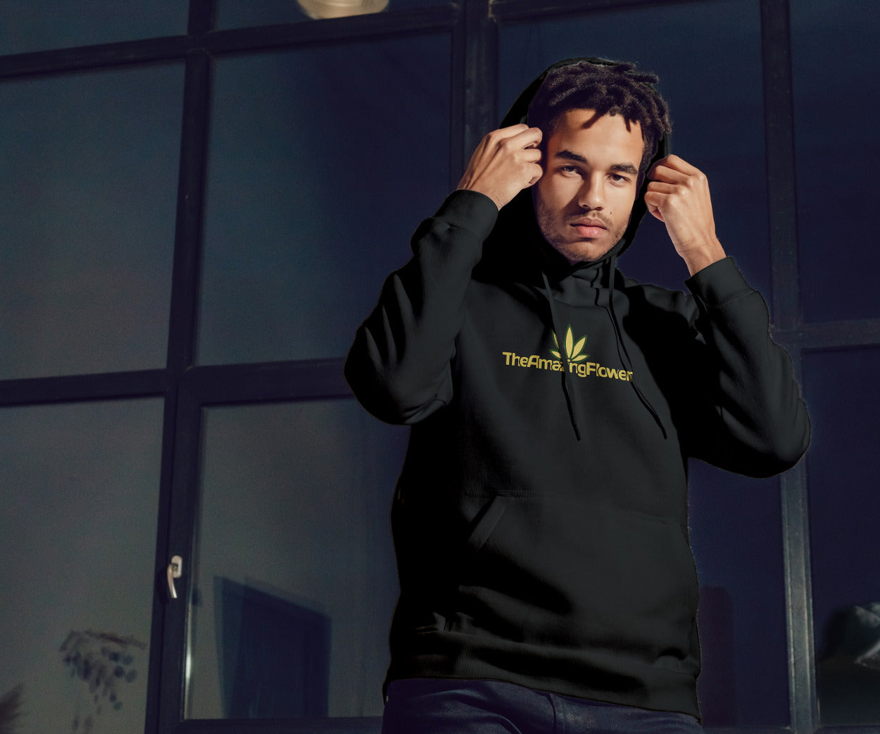 Old Gold Hemp Leaf Logo Pullover Hoodie in black worn by a man in front of an office pulling his hood up while looking at the camera.