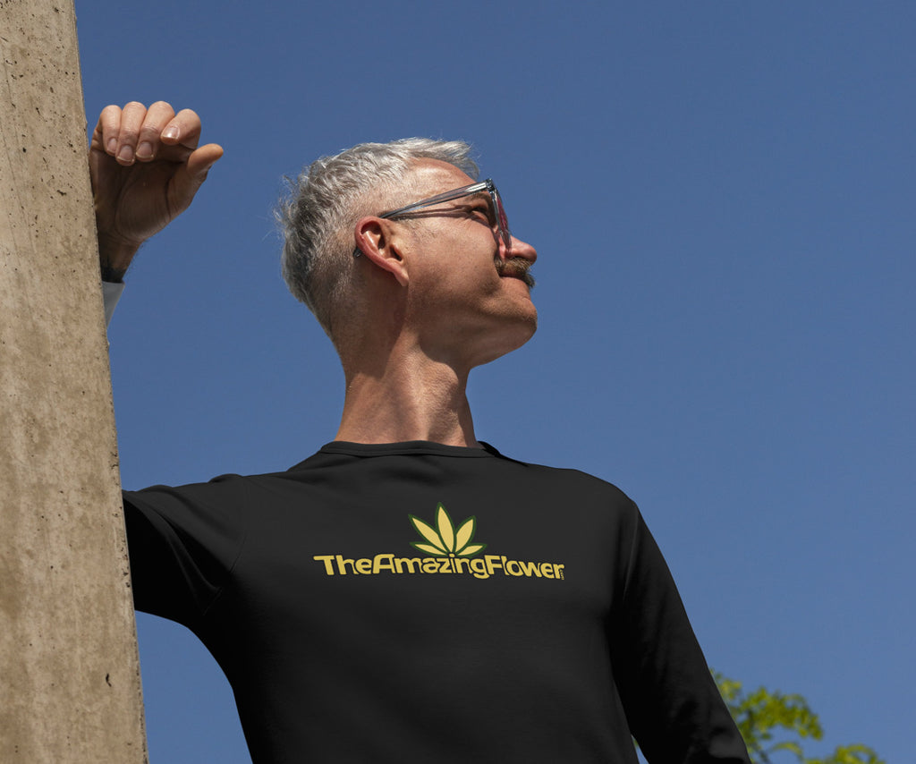 Old Gold Hemp Leaf Logo Long Sleeve T-Shirt in black worn by a man with grey hair and glasses as he leans against a post looking out to his left