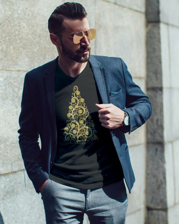 Man with a beard and sunglasses standing in the sun next to a granite block building, wearing a blue denim blazer over a black cannabis Christmas tree t-shirt with gold finial style tree